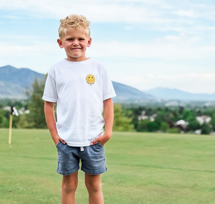 Young boy standing on a grassy field with mountains in the background