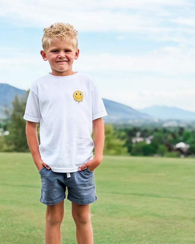Young boy standing on a grassy field with mountains in the background