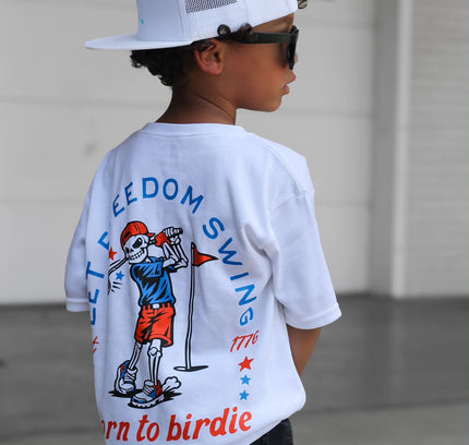 Child wearing a white t-shirt with a graphic design and text, standing in an indoor setting.