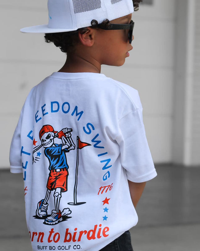 Child wearing a white t-shirt with a graphic design and text, standing in an indoor setting.