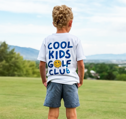 Child wearing a 'Cool Kids Golf Club' t-shirt on a golf course
