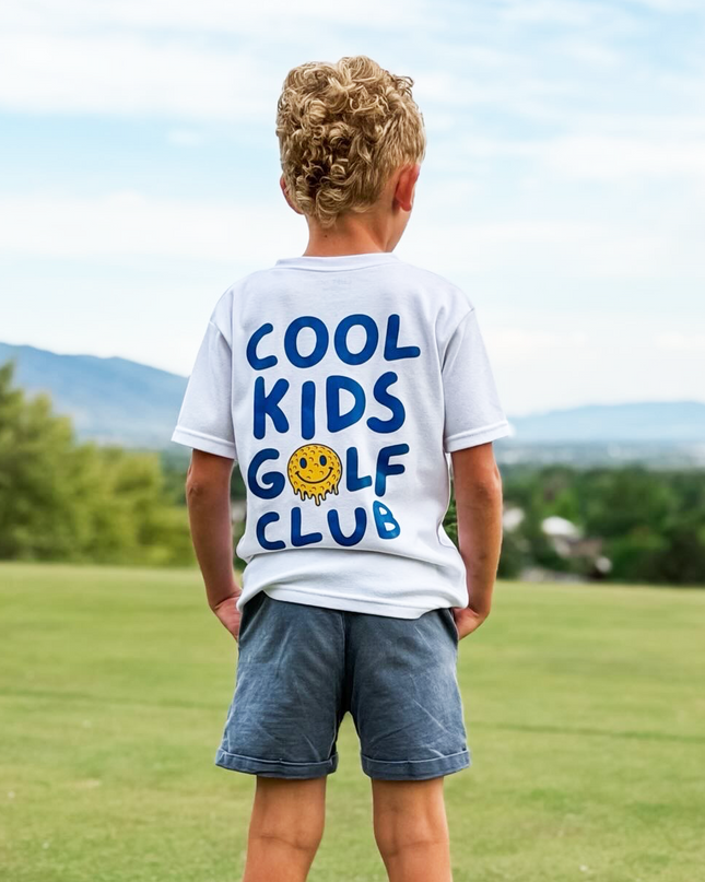 Child wearing a 'Cool Kids Golf Club' t-shirt on a golf course