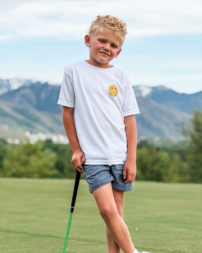Young boy holding a golf club on a golf course with mountains in the background