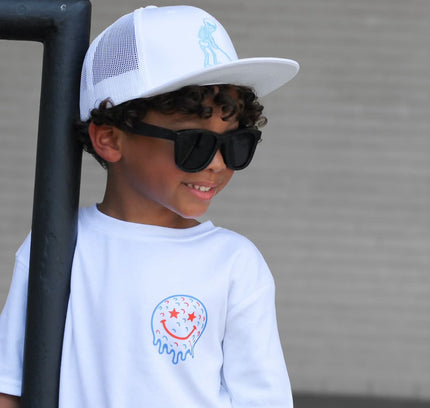 Child wearing a white cap and sunglasses with a plain background