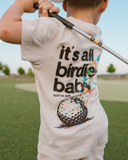 Child wearing a t-shirt with a golf-themed design on a golf course