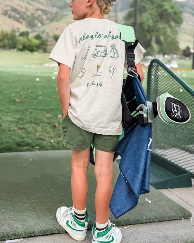 Child holding a golf club on a golf course with mountains in the background