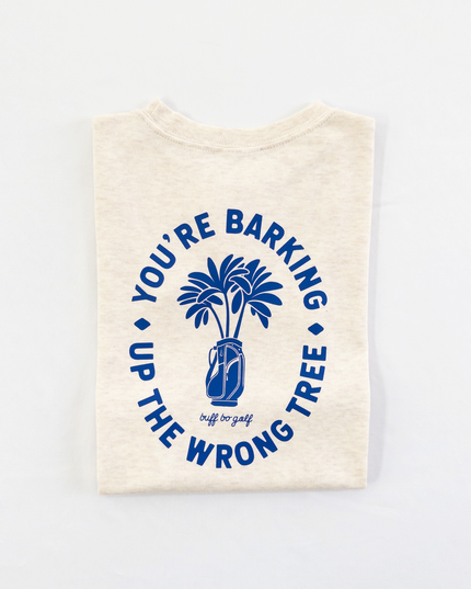Beige kids golf t-shirt featuring bold blue graphic with palm trees in a golf bag and playful text reading 'You're Barking Up The Wrong Tree,' from Buff Bo Golf apparel collection, displayed on a light background.