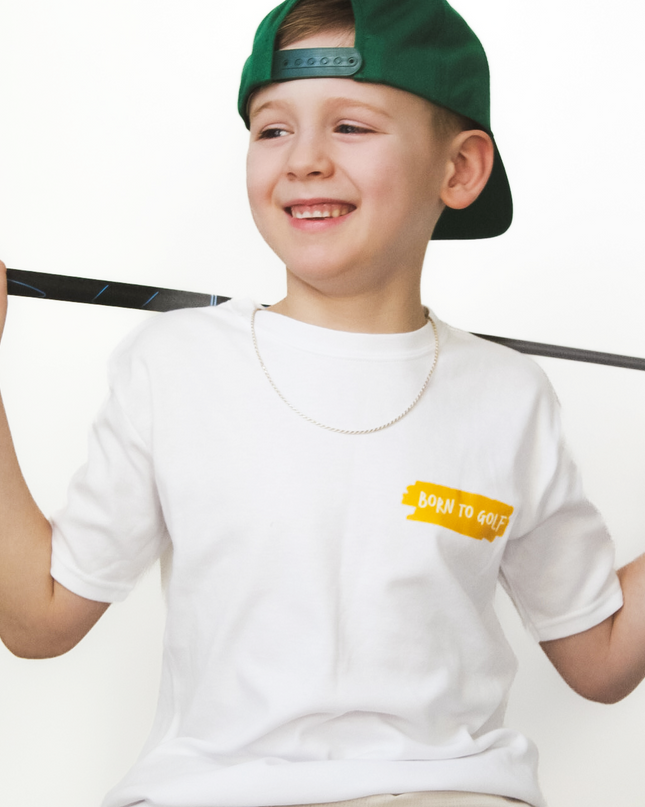 Child wearing a white t-shirt with a logo and a green cap, sitting on a white background