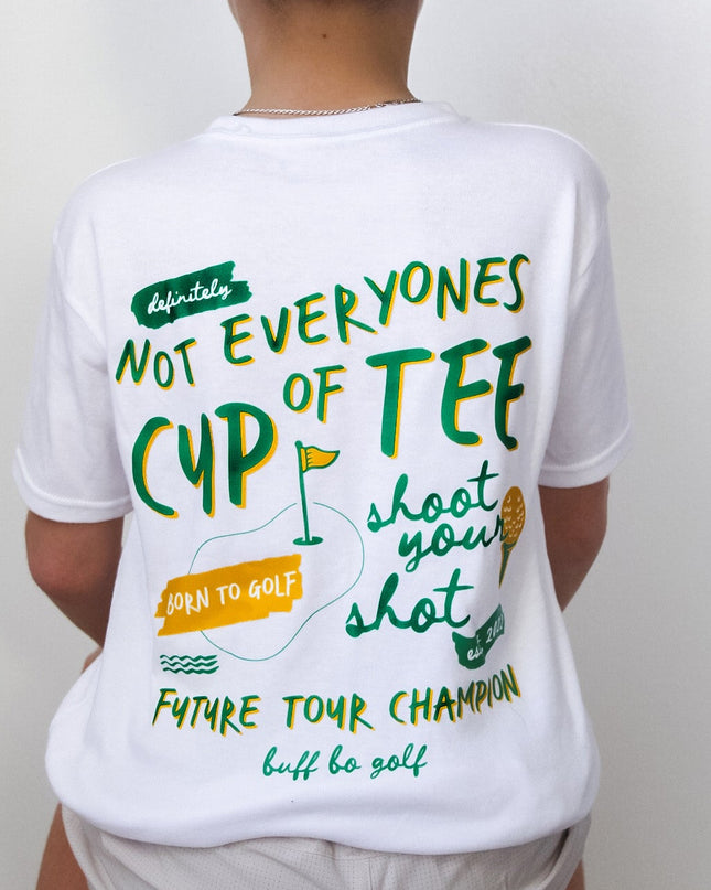 Person wearing a white t-shirt with humorous golf-themed text and a green 'GOLF' cap.