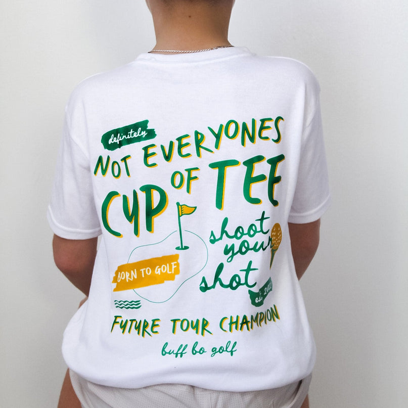 Person wearing a white t-shirt with humorous golf-themed text and a green 'GOLF' cap.