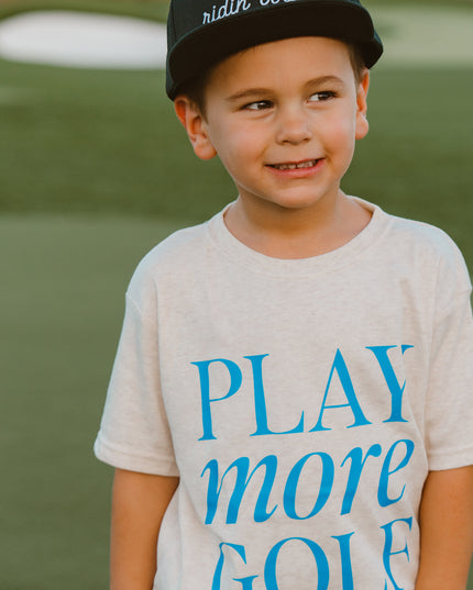 Child wearing a t-shirt with 'Play more golf' on a golf course