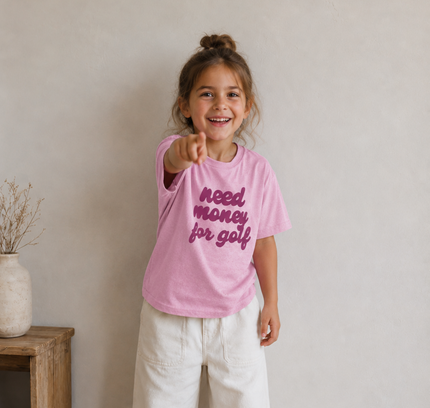 Child wearing a pink t-shirt with text, standing indoors.