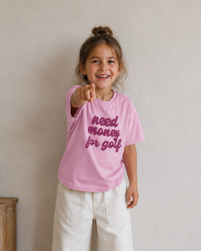 Child wearing a pink t-shirt with text, standing indoors.