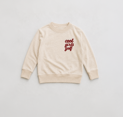 A cream-colored long-sleeve crewneck sweatshirt with 'cool girls golf' printed in red script on the left chest, displayed flat against a light gray background.