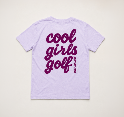 A light lavender short-sleeve t-shirt shown from the back, featuring the words 'cool girls golf' printed in a dark purple script font, with 'BUFF DO GOLF' written vertically in smaller text next to it.