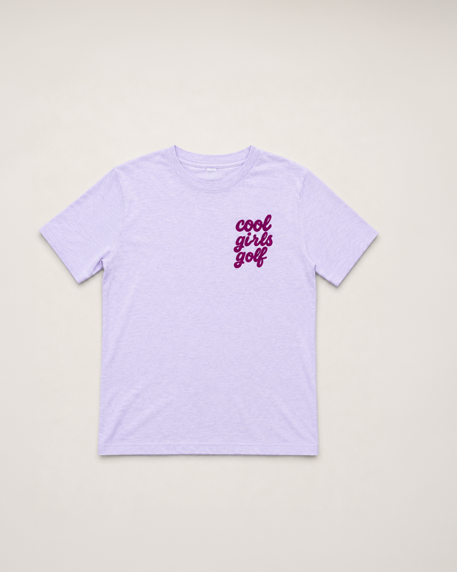 A light purple short-sleeve t-shirt with 'cool girls golf' printed in a dark purple cursive font on the left chest, displayed flat against a light beige background.