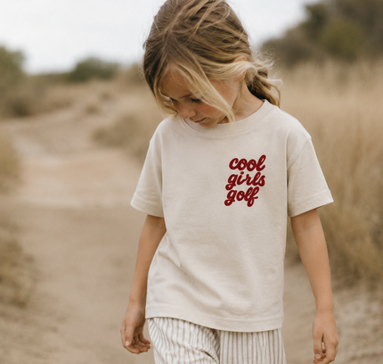 Child wearing a 'cool girls golf' t-shirt in a desert setting