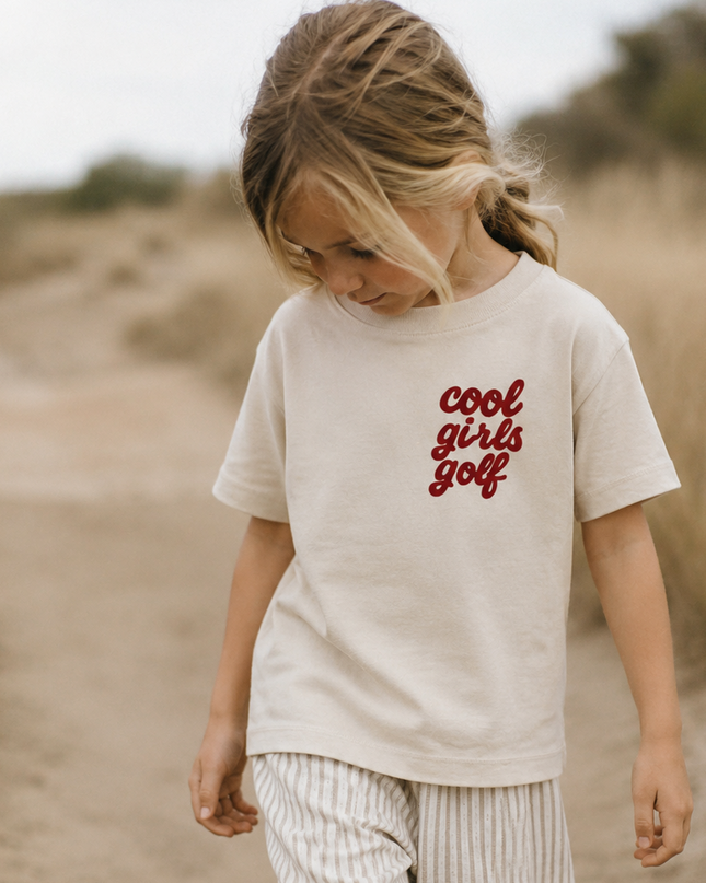 Child wearing a 'cool girls golf' t-shirt in a desert setting