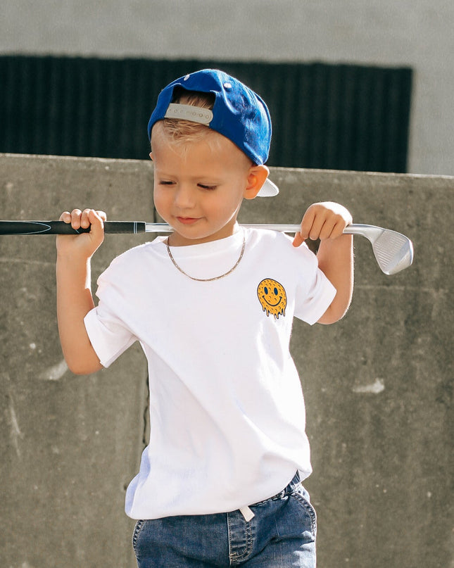 Child holding a baseball bat and glove against a concrete wall