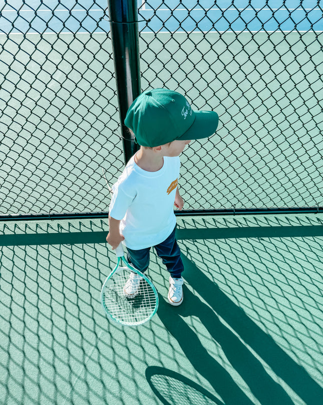 Child holding a tennis racket on a tennis court