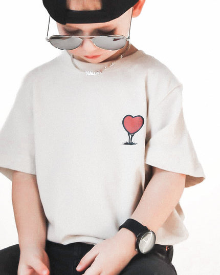Child wearing a white t-shirt with a red heart design, black pants, and sunglasses on a white background