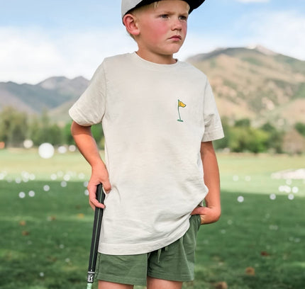Young boy on a golf course with mountains in the background