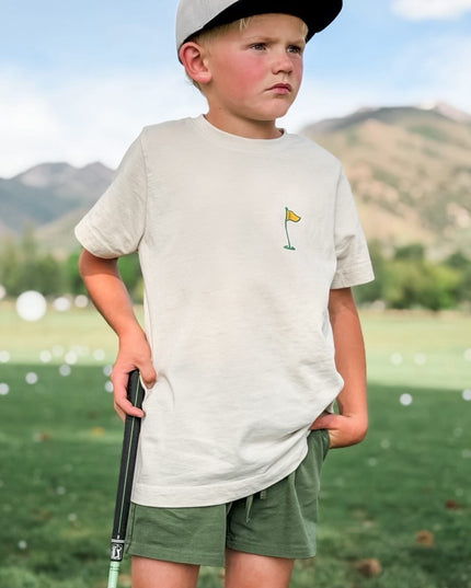 Young boy on a golf course with mountains in the background