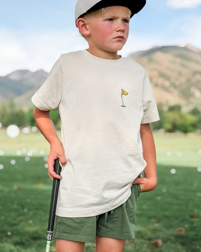 Young boy on a golf course with mountains in the background
