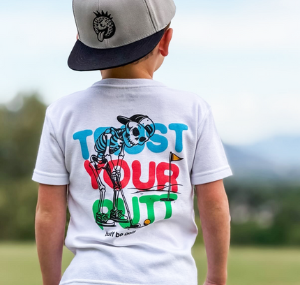 Child wearing a white t-shirt with colorful text and graphics outdoors