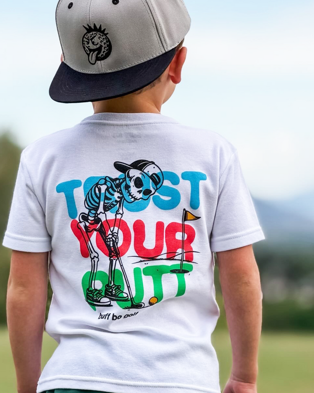 Child wearing a white t-shirt with colorful text and graphics outdoors