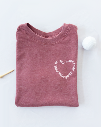 Folded maroon shirt with white text on a light gray background