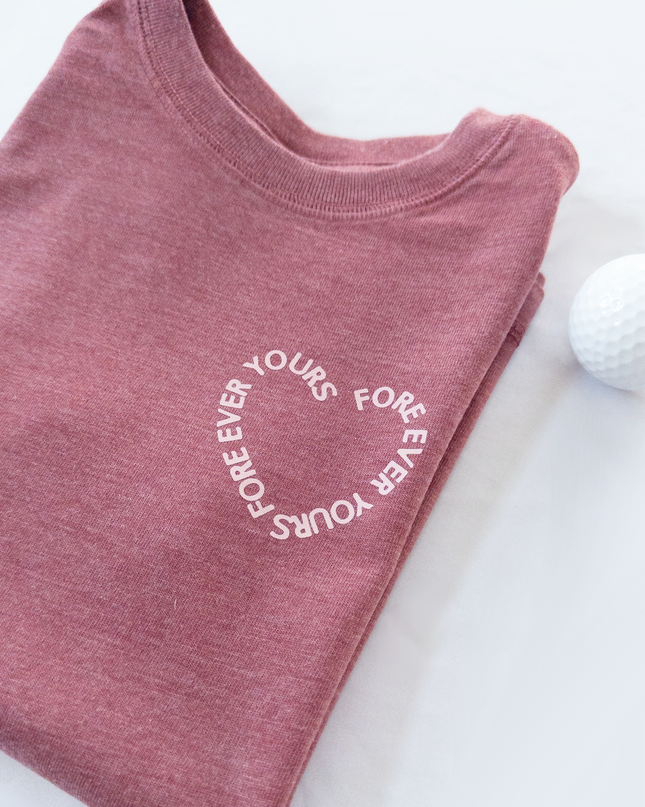 Folded pink t-shirt with 'FOREVER YOURS' text on a white background