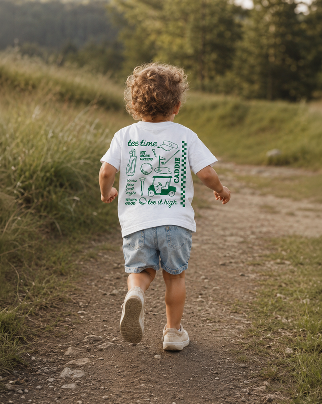 Child walking on a dirt path in a natural setting with a t-shirt featuring text and graphics.
