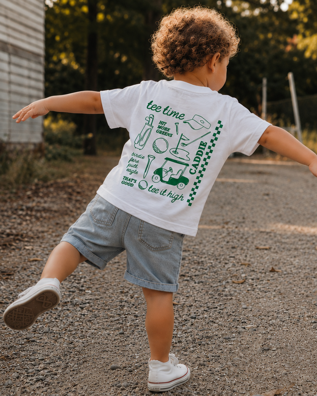 Child running on a road wearing a white t-shirt with green graphics and text.