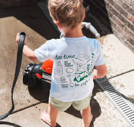 Child holding a garden hose on a patio