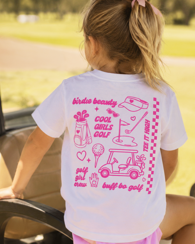 Child wearing a white t-shirt with pink graphics and text, sitting in a golf cart.