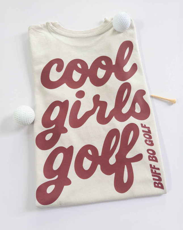 Beige t-shirt with 'cool girls golf' text and golf club on a white background