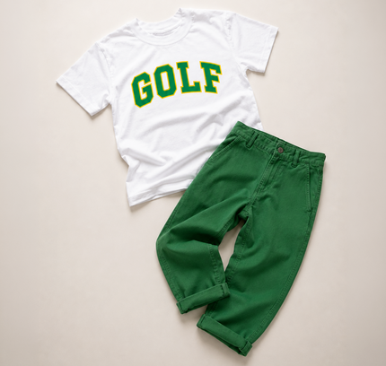 A children's two-piece outfit laid flat on a light beige background, featuring a white short-sleeve T-shirt with 'GOLF' printed in green and yellow varsity lettering, paired with bright green pants.