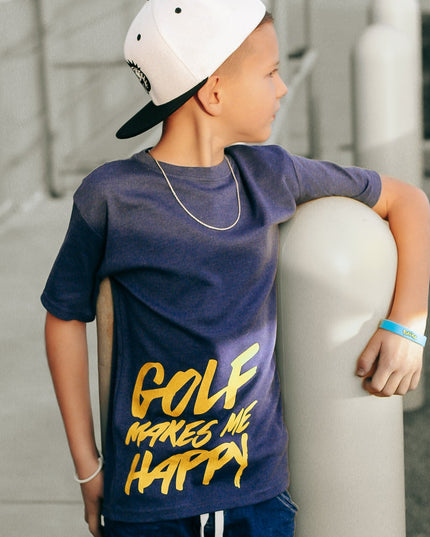 Child wearing a navy blue t-shirt with 'Golf Makes Me Happy' text, leaning against a pole.
