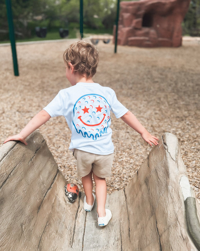 Child climbing on playground equipment wearing a white t-shirt with a colorful design.