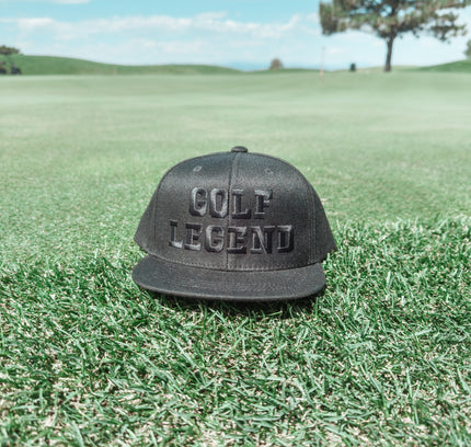 Black cap with 'GOLF LEGEND' text on a grassy field