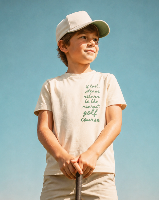 Young boy holding a golf club on a golf course with a clear blue sky.