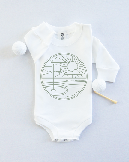 White long-sleeve baby onesie featuring a minimalist golf course design with a flag, sun, and clouds. The onesie is laid flat with two golf balls and a wooden tee beside it.