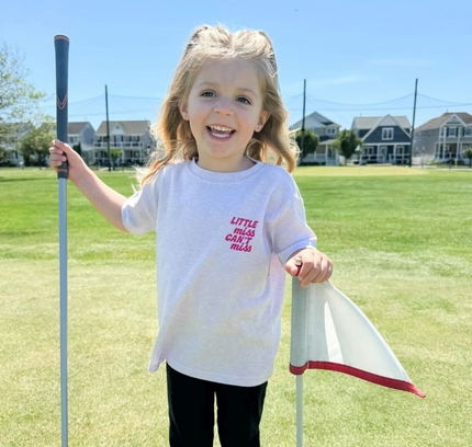 Child holding a golf club and flag on a golf course