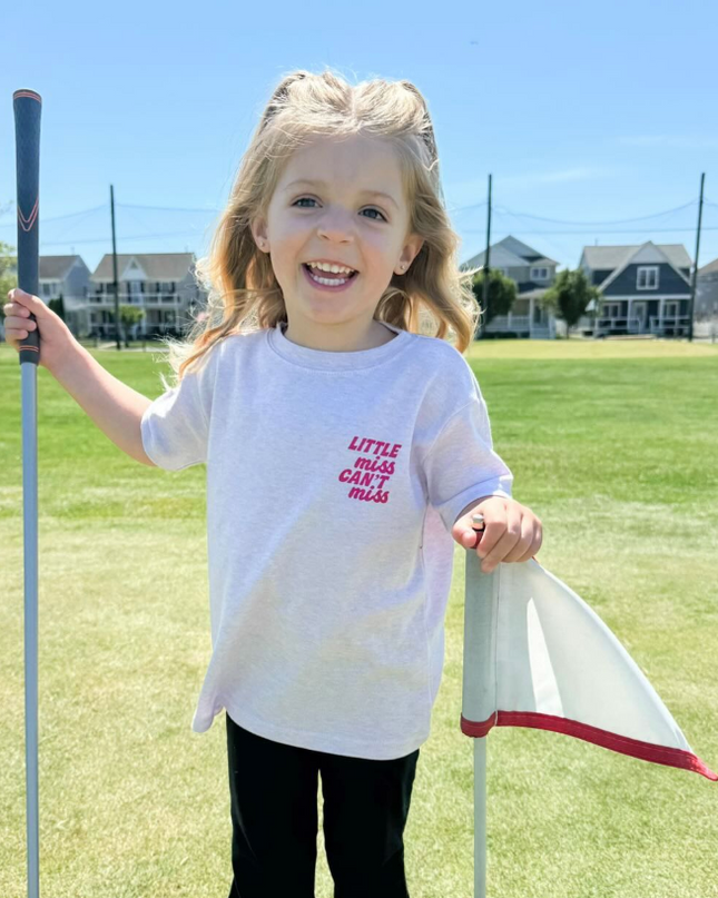 Child holding a golf club and flag on a golf course