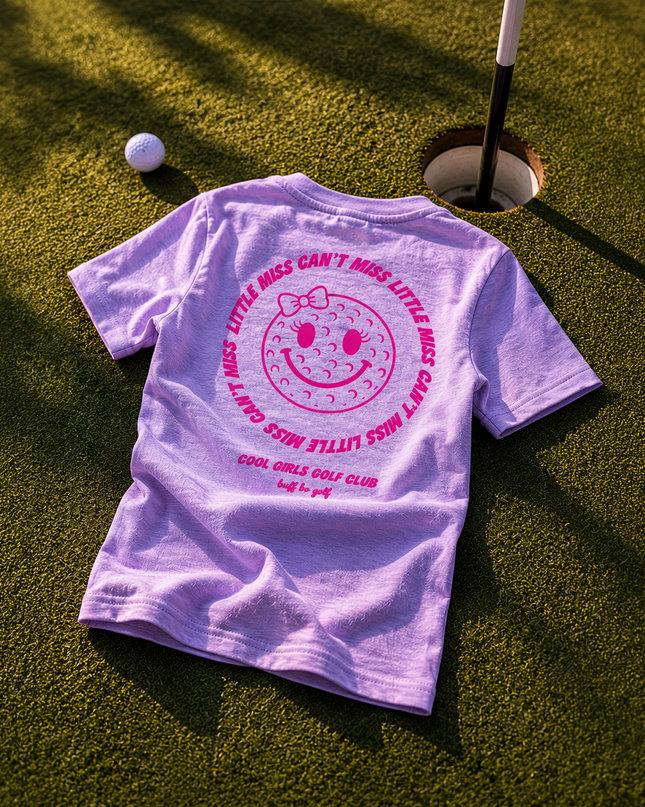 Purple t-shirt with a smiley face design on a golf course