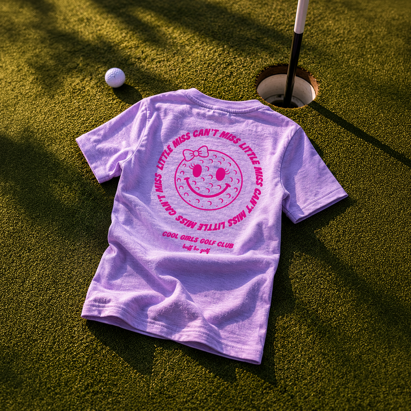 Purple t-shirt with a smiley face design on a golf course