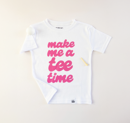 White t-shirt with pink text 'make me a tee time' on a light background