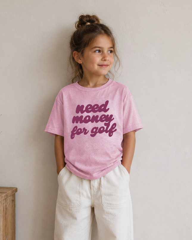 Young girl wearing a pink t-shirt with text, standing against a plain wall.