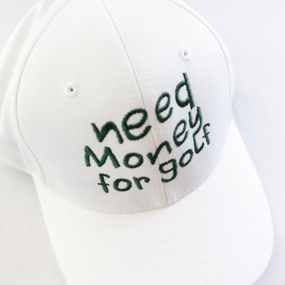 White golf hat featuring playful dark green embroidered text 'need money for golf,' fun and casual headwear for young golfers and golf enthusiasts, displayed on a light neutral background.
